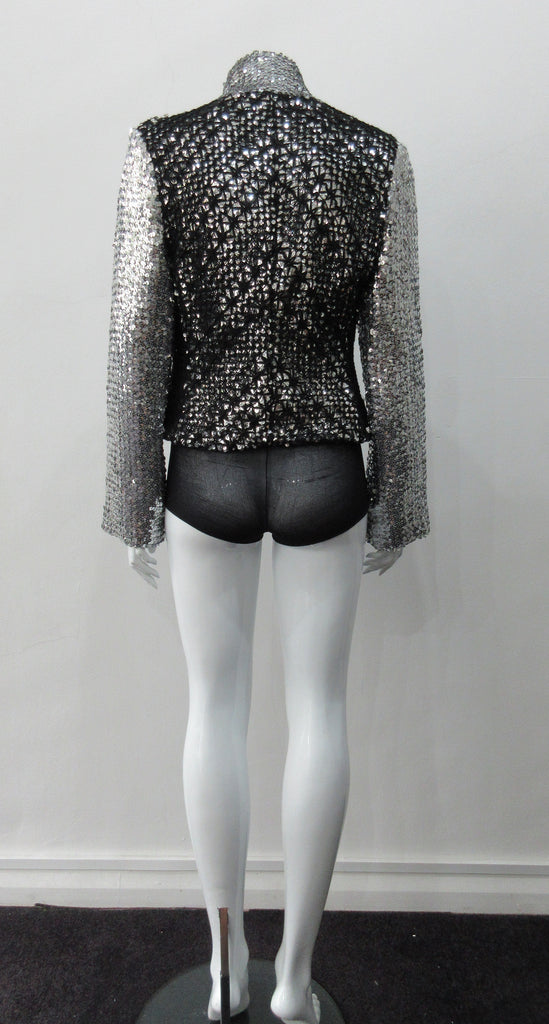 Silver Glitter Jacket with Black Crochet. Full on glittered siver colour sequin jacket with partblack crochet covered for a sporty feel. Crochet detailing unravelling/fraying in areas as done for intentional effect. CF zipper with 8.5cm high collar. CB length 52cm. Sleeve length from side neck point 76cm. 950g approximate weight. 90% Polyester, 5% Elastine, 5% Metallic Contrast: 100% Cotton. Lining: 100% Polyester. Dry Clean Only. Made in England