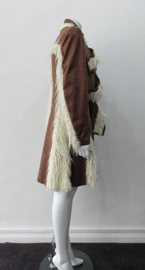 Split Suede Coat. Faux suede coat with faux fur contrast trim on lapels and inside. Flared towards hem with contrast faux fur panels. Rich saddle lighter brown colour. Feminine version inspired from 18th century men's evening coat. Multiple ways of buttoning as illustrated. Can be paired with 060301 Brown Suede Trouser. Formerly a showpiece, specially made. No Label. CB Length 94cm. Sleeve length from side shoulder point 75cm. 850g approximate weight. 95% Polyester, 5% Rayon. Contrast: 100% Viscose. Dry Cl