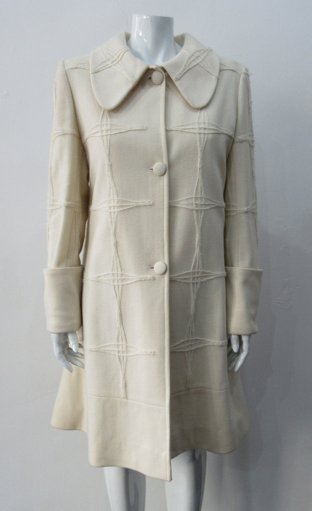 Generously cut 3/4 length coat with large rounded collar and covered buttons in off white, with a slight military feel. Features neo-classical trim design which naturally becomes fuzzy over time as a design detail. Size 12