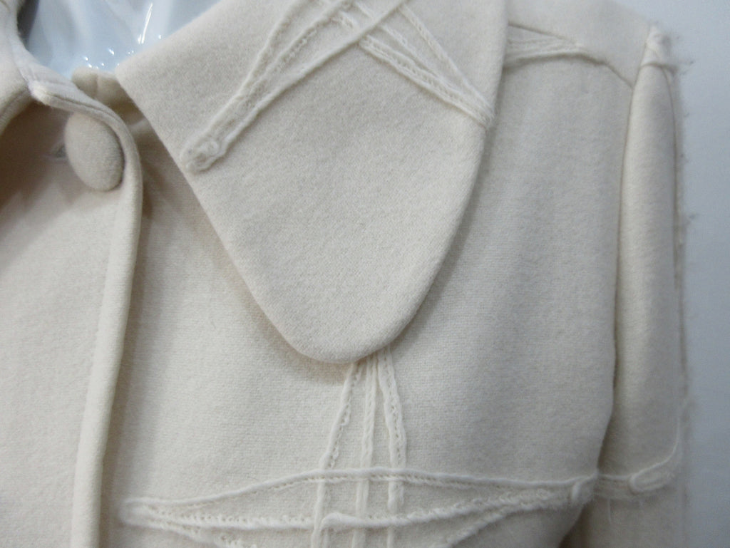 Generously cut 3/4 length coat with large rounded collar and covered buttons in off white, with a slight military feel. Features neo-classical trim design which naturally becomes fuzzy over time as a design detail. Size 12