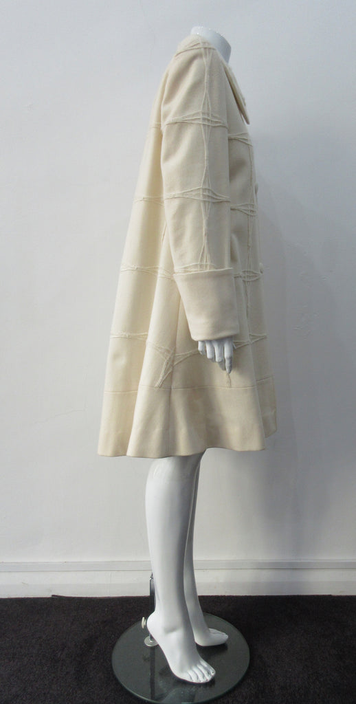 Generously cut 3/4 length coat with large rounded collar and covered buttons in off white, with a slight military feel. Features neo-classical trim design which naturally becomes fuzzy over time as a design detail. Size 12