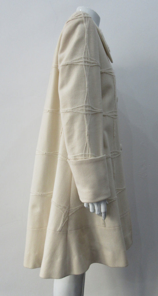 Generously cut 3/4 length coat with large rounded collar and covered buttons in off white, with a slight military feel. Features neo-classical trim design which naturally becomes fuzzy over time as a design detail. Size 12