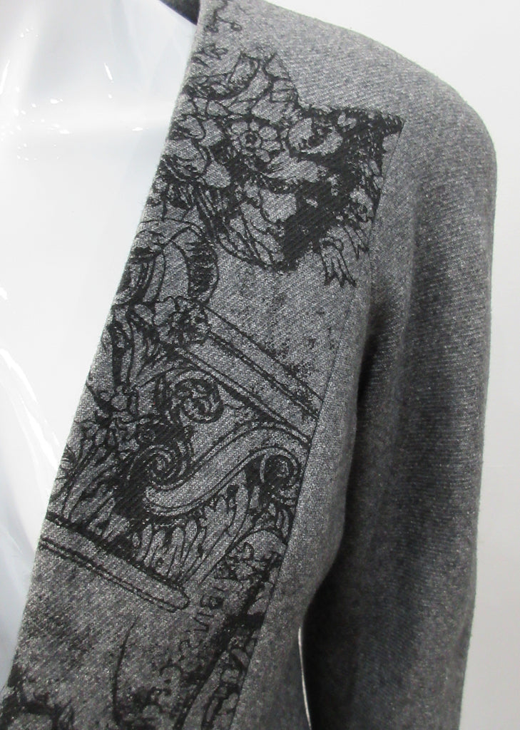 False Peak Jacket. Old-School Jacket in charcoal grey with rounded shoulders. Design features sewn in collar and lapel. Covered buttons throughout. Relaxed fit. Size 8