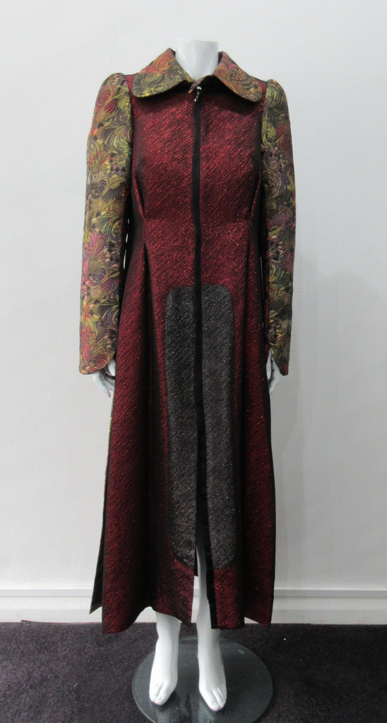 Belted Coat. Full length multi-textured, multi-paneled coat in a variety of brocades in gold, brass, red & black. CF metal zipper concealed behind black satin trim. 4.5cm tie belt attached to coat at side seams. 59cm side hem slits. Reverse pleats on front below waist for bit more ease. CB Coat length 131cm. Sleeve length from side neck point 78cm. 48% Acetate, 32% Cotton, 10% Viscose, 10% Lurex. Contrast: 65% Cotton, 35% Polyester. Lining 100% Rayon. Dry Clean Only. Made in England