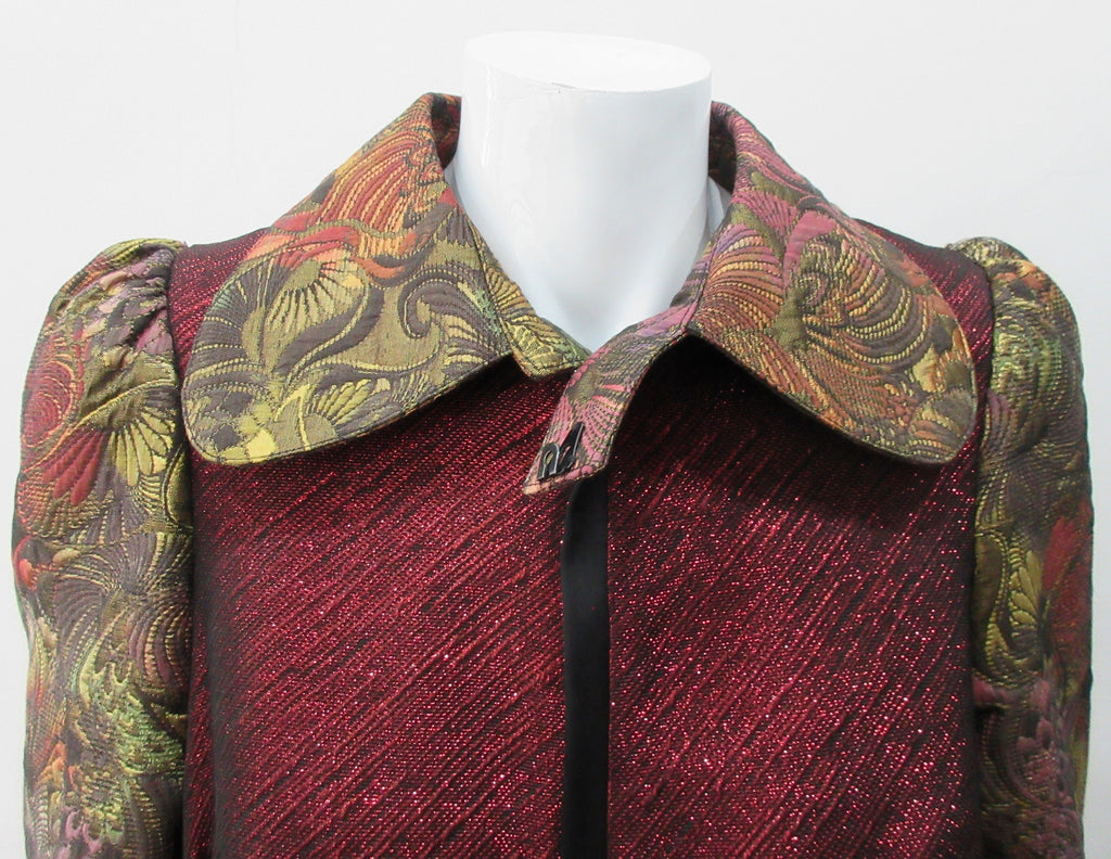 Belted Coat. Full length multi-textured, multi-paneled coat in a variety of brocades in gold, brass, red & black. CF metal zipper concealed behind black satin trim. 4.5cm tie belt attached to coat at side seams. 59cm side hem slits. Reverse pleats on front below waist for bit more ease. CB Coat length 131cm. Sleeve length from side neck point 78cm. 48% Acetate, 32% Cotton, 10% Viscose, 10% Lurex. Contrast: 65% Cotton, 35% Polyester. Lining 100% Rayon. Dry Clean Only. Made in England