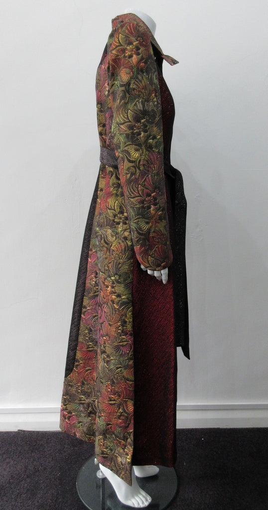Belted Coat. Full length multi-textured, multi-paneled coat in a variety of brocades in gold, brass, red & black. CF metal zipper concealed behind black satin trim. 4.5cm tie belt attached to coat at side seams. 59cm side hem slits. Reverse pleats on front below waist for bit more ease. CB Coat length 131cm. Sleeve length from side neck point 78cm. 48% Acetate, 32% Cotton, 10% Viscose, 10% Lurex. Contrast: 65% Cotton, 35% Polyester. Lining 100% Rayon. Dry Clean Only. Made in England