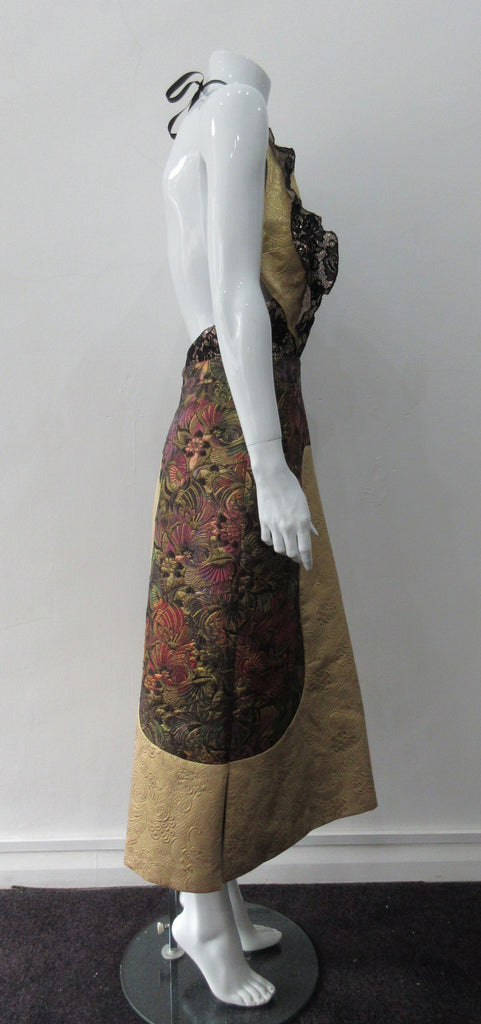 Gold Sleveless Slit Dress. Extreme cutaway CF slit dress with tie-neck. Low cut away back with invisible zipper. Covers side bust and frills on side fronts. CF Dress length from neckpoint 110cm. 350g approximate weight. 59% Cotton, 41% Nylon. Contrast: 65% Cotton, 35% Polyester. Lining: 100% Rayon. Dry Clean Only. Made in England