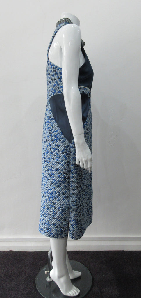 Zoom Dress. Cut away dark blue sleevelss dress featurung geometric panels in stretch jersey and multi-coloured textured hexagon design. CF seperation gap with 4cm high silver sequined collar. Silver piping across front of dress. Shorter version of 170610L Zoom Dress. CB Dress Length from neck point 108cm. 450g approximate weight. 81% Polyester, 19% Polyamide Contrast: 80% Silk, 17% Polyamide, 3% Elastine. Lining: 100% Viscose. Dry Clean. Only Made in England