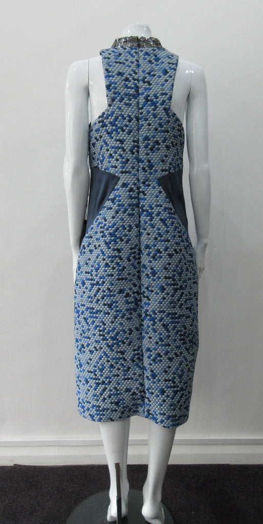 Zoom Dress. Cut away dark blue sleevelss dress featurung geometric panels in stretch jersey and multi-coloured textured hexagon design. CF seperation gap with 4cm high silver sequined collar. Silver piping across front of dress. Shorter version of 170610L Zoom Dress. CB Dress Length from neck point 108cm. 450g approximate weight. 81% Polyester, 19% Polyamide Contrast: 80% Silk, 17% Polyamide, 3% Elastine. Lining: 100% Viscose. Dry Clean. Only Made in England