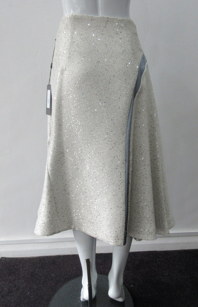 Plain Curve Panel Skirt Assymetrical gathered toggled skrit in grey-white colour. Grey seam panel can be gathered to create raised ruching effect. Featuring textured tweed style with spaced sequins. Large metal side front detaching zipper. CB length 80cm. 600g approximate weight. 36% Polyester, 28% Viscose, 35% Cotton, 5% Lycra. Dry Clean Only. Made in England