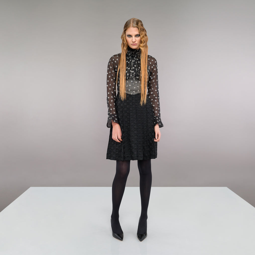 Medium length long sleeve dress featuring high ruched collar and gathered front bodice to waist panel. Sheer black with white tri-circular design. Slight fraying on collar natural part or ruching effect. Fully pleated below waist panel in solid black textured fabric. 700g approximate weight. 93% Acrylic, 7% Lycra. Contrast: 81% Polyester, 14% Polyamide, 5% Elastine. Dry Clean Only. Made in England