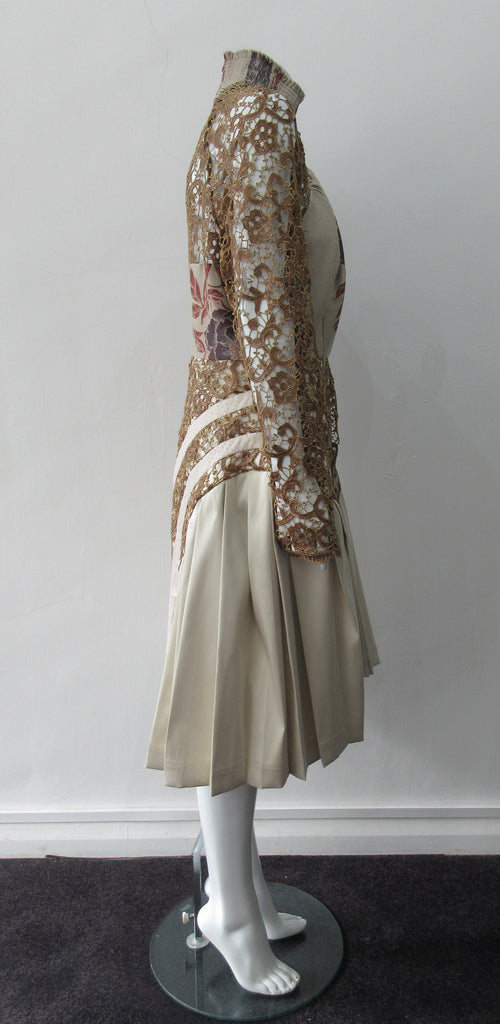 Floral Tri-Point Swing Dress. Intese pleated A-line pleated swing dress in Beige. Contrast sequined and beaded gold lace contrast panels. Subtle floral design on bodice. Full pleats below hip. CB invisible zipper. High ruched collar 6.5cm height. CB length from neck point 105cm. 1kg approximate weight. 100% Polyester, Contrast: 41% Polyester, 26% Acrylic, 26% Wool, 7% Polyamide Lining: 100% Rayon. Dry Clean Only. Made in England