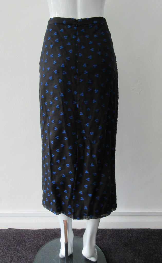 Dark Curve Front Pencil Skirt. Slightly tighter pencil-style fit skirt in sheer black with tri-blue dot design, and black faux leather textured weave design. Can be paired with 180609B Dark Gathered Top. CB length to hem 79cm. 32cm concealed vent bottom of skirt. 400g approximate weight. Fully lined. 90% Polyester, 10% Cotton. Contrast: 100% Polyester. Dry Clean Only. Made in England