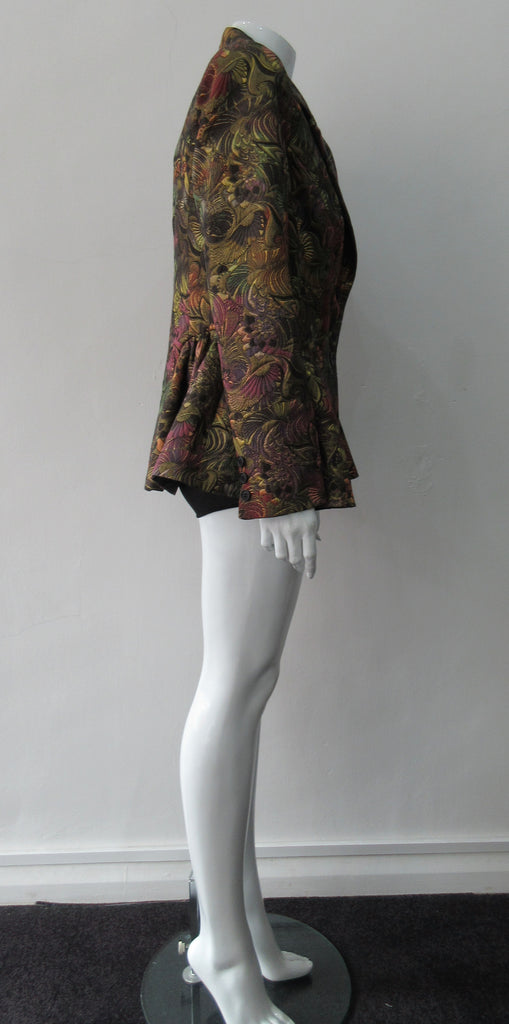 Sahara Jacket. Brass red and purlple textured brocade jacket featuring side hip gathers and 2 button front clousure. CB Length from neck point 67cm. 65% Cotton, 36% Polyester. Lining: 100% Rayon. Dry Clean Only. Made in England