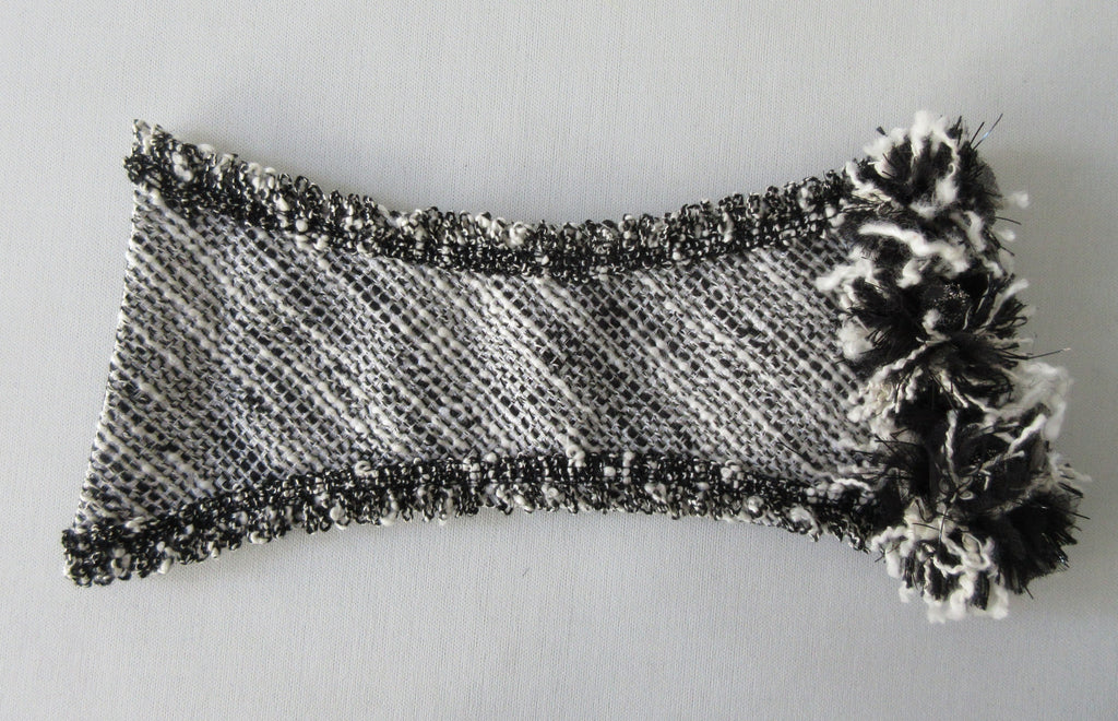 Black & White Tweed style weave, with frayed detail on edge, 100% wool with 100% Cotton inner back lining. Snap Closure. Size M -17cm from snap to snap width Size L -18cm from snap to snap width. 60g approximate weight, comes in white box. Made in France
