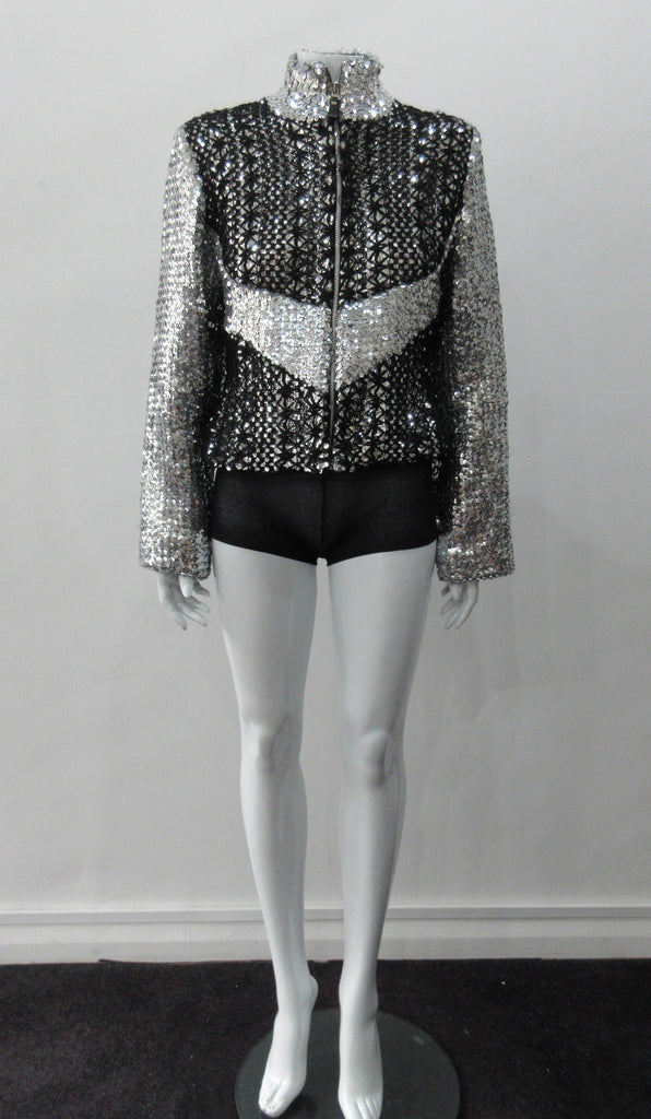 Silver Glitter Jacket with Black Crochet. Full on glittered siver colour sequin jacket with partblack crochet covered for a sporty feel. Crochet detailing unravelling/fraying in areas as done for intentional effect. CF zipper with 8.5cm high collar.  CB length 52cm. Sleeve length from side neck point 76cm. 950g approximate weight. 90% Polyester, 5% Elastine, 5% Metallic Contrast: 100% Cotton. Lining: 100% Polyester. Dry Clean Only. Made in England