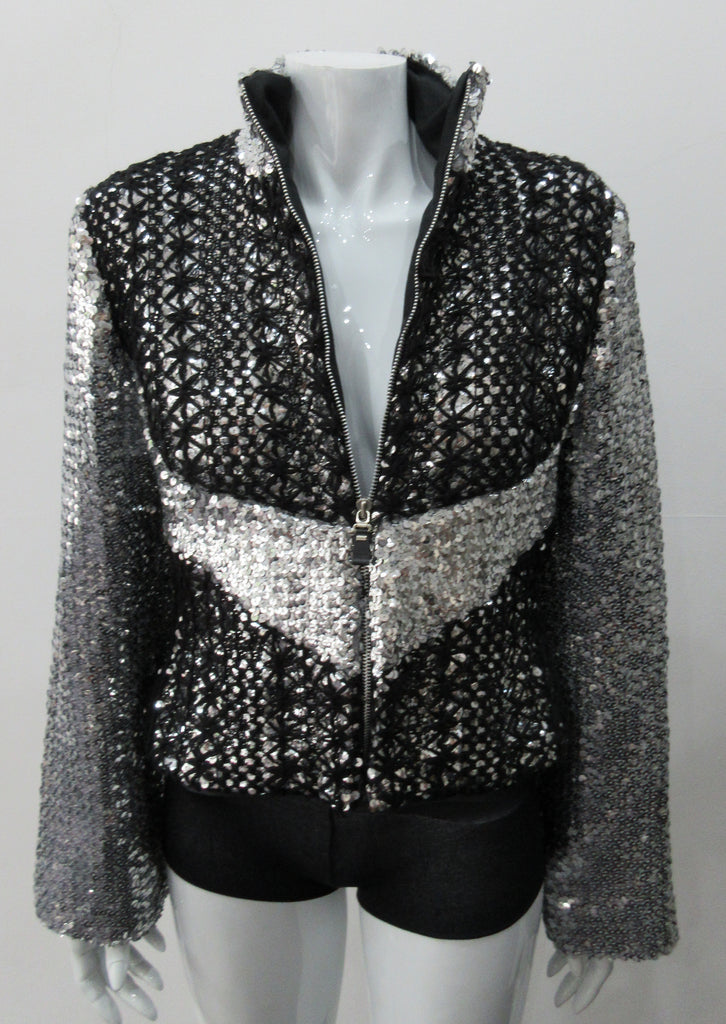 Silver Glitter Jacket with Black Crochet. Full on glittered siver colour sequin jacket with partblack crochet covered for a sporty feel. Crochet detailing unravelling/fraying in areas as done for intentional effect. CF zipper with 8.5cm high collar.  CB length 52cm. Sleeve length from side neck point 76cm. 950g approximate weight. 90% Polyester, 5% Elastine, 5% Metallic Contrast: 100% Cotton. Lining: 100% Polyester. Dry Clean Only. Made in England