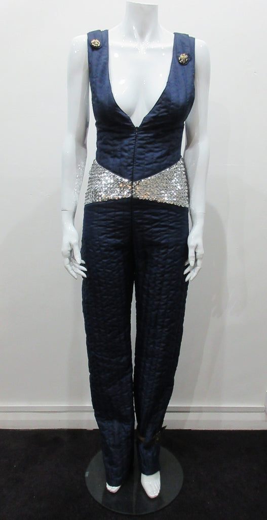 Full length one-piece brace jumpsuit with a sequin contrast panel. Twin brocade buttons on shoulder points.