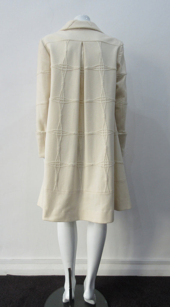 Generously cut 3/4 length coat with large rounded collar and covered buttons in off white, with a slight military feel. Features neo-classical trim design which naturally becomes fuzzy over time as a design detail. Size 12