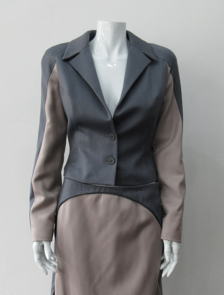 Cropped Point Sleeve Jacket. Pointed peak collared cropped style in grey with light taupe/rose contrast sleeve panels. Relaxed fit with soft raglan sleeves. Shown with matching skirt. Size 8. 100% Wool. Lining: 100% Rayon, Dry Clean Only. Made in England