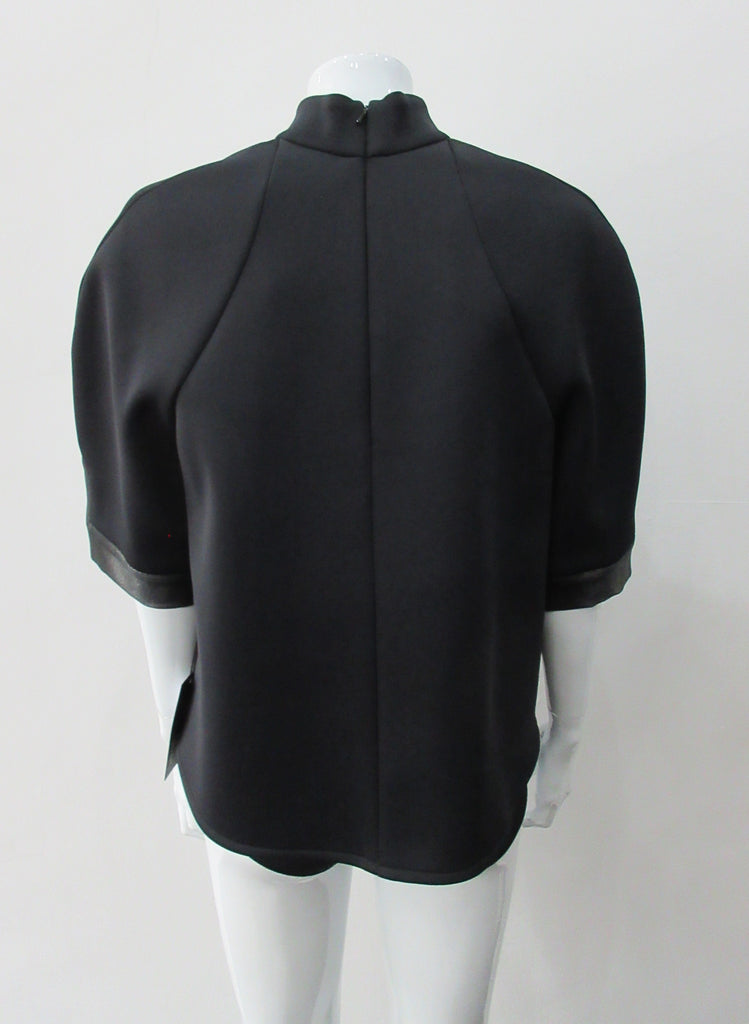 Black Crop Top. Cropped raglan sleeve top in medium weight scuba with contast charcoal colour, shiny fabric front.  Medium sleeves with charcoal shiny contrast trim on sleeve hems.  5cm high collar. CB invisible zipper. CB neck point length 57cm 350g approximate weight.  85% Polyamide, 15% Elastine. Contrast: 98% Nylon, 2% Lycra. Dry Clean Only. Made in England