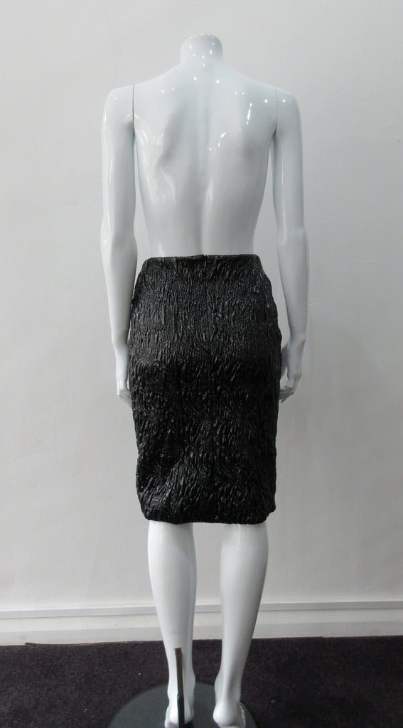 Shiny Ruched Skirt. PVC style curved linear ruching technique creating textured stretch in black. CB invisible zipper and stretch lining. Good for fetish wear. CB length 58cm. 250g approximate weight 90% Polyeurethane, 10% Cotton. Lining: 100% Viscose. Dry Clean Only. Made in Canada