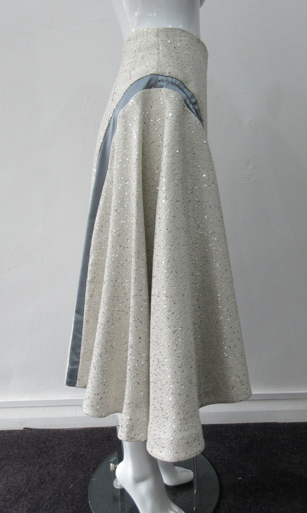 Plain Curve Panel Skirt  Assymetrical gathered toggled skrit in grey-white colour. Grey seam panel can be gathered to create raised ruching effect. Featuring textured tweed style with spaced sequins. Large metal side front detaching zipper. CB length 80cm. 600g approximate weight. 36% Polyester, 28% Viscose, 35% Cotton, 5% Lycra. Dry Clean Only. Made in England