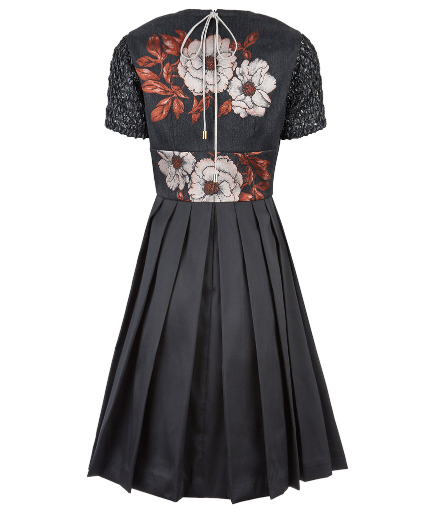 Upper floral tri-point neckline dress in 3/4 length, featuring pleated lower part of dress below waist in black satin. Contrast black faux leather textured mesh sleeves. CB zipper and contrast string around neckline. 450g approximate weight. 41% Polyester, 26% Acrylic, 7% Polyamide. Dry Clean Only. Made in England