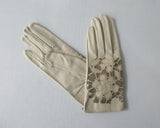 Tan Floral Cutout Gloves. Item Number D540NSF C1PRIA S357 0574. Tan Leather Gloves with floral cut-out design on top hand. 60g approximate weight. Made in Italy
