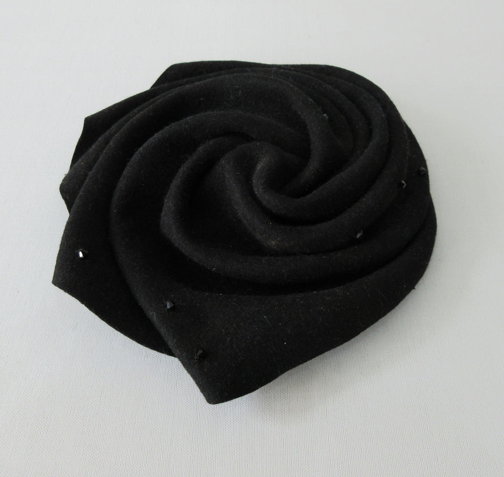 Olka Hats Black Felt Twirled Mini Black Felt Twirled with Black Rinestones, and elastic for chin. Retro style can be worn on top or side of head. 20cm x 21cm inside diameter. 30g approximate weight. Made in Canada