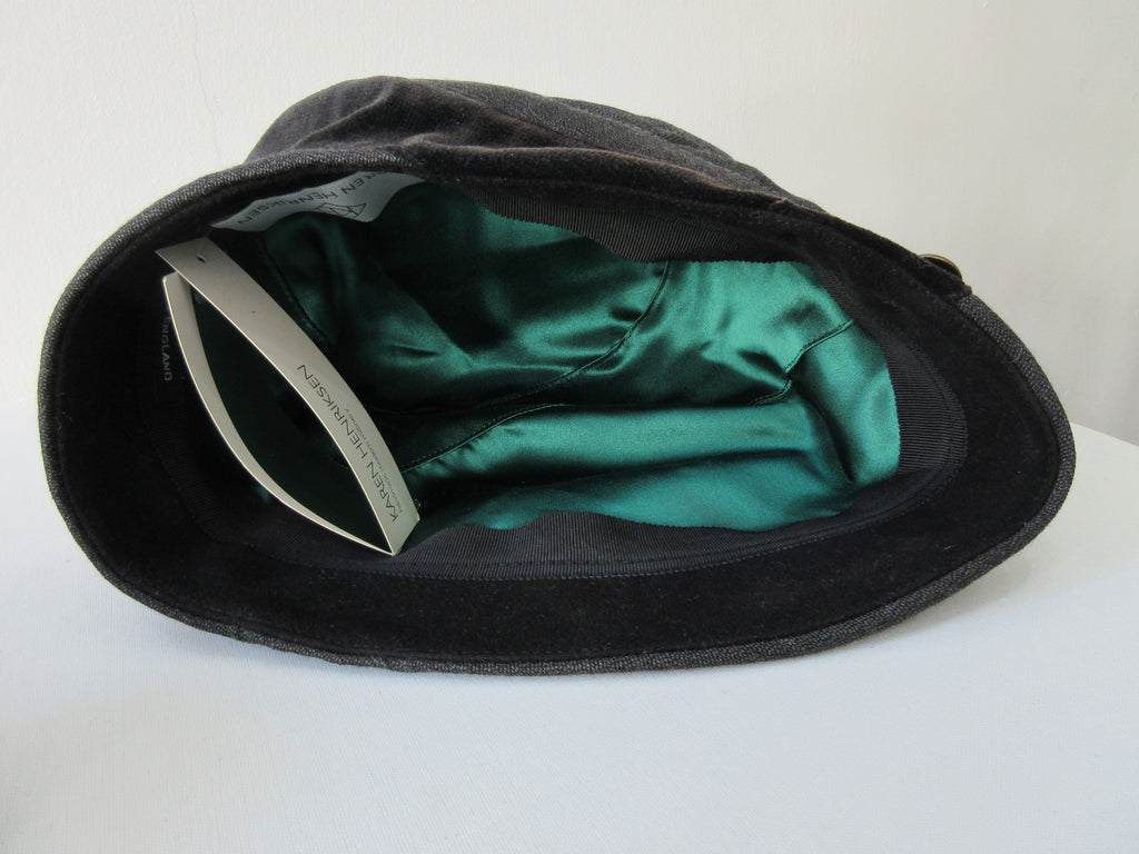 Karen Henricksen Savoy Hat. Heavy Charcoal coloured panels with velvet stripe. With 7 brass buttons. Bright green inside satin lining. Size unknown, inside diameter 59.5cm. Height 18cm in highest angle, 12cm on lowest angle. 35g approximate weight. Made in England